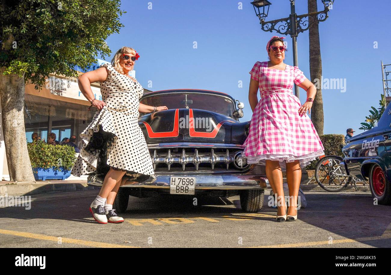 Due donne vestite in stile anni cinquanta in posa di fronte a una vecchia auto d'epoca al Rockin Race Jamboree Festival 2024, rockabillies, Torremolinos, Spagna. Foto Stock