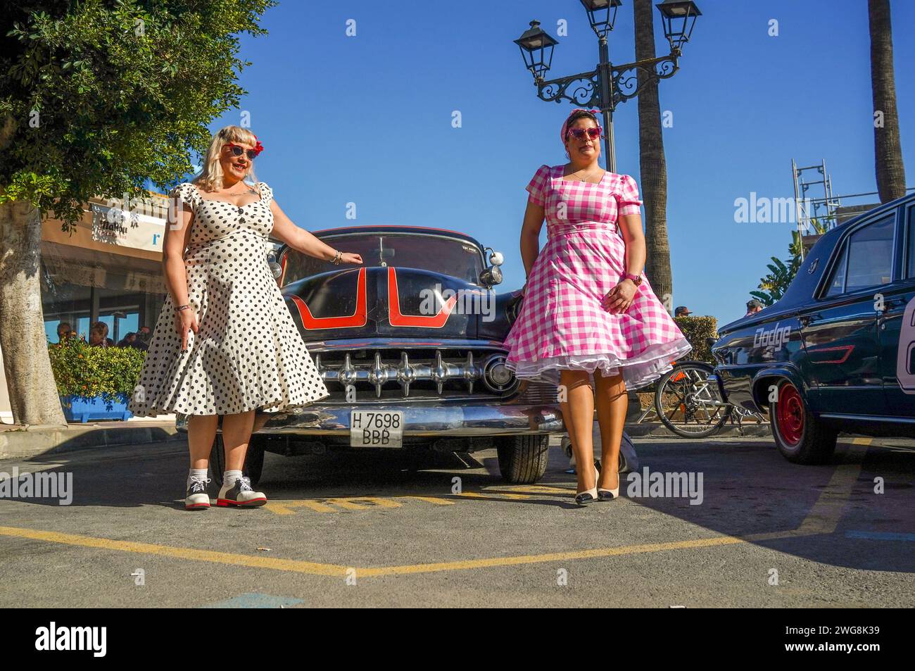 Due donne vestite in stile anni cinquanta in posa di fronte a una vecchia auto d'epoca al Rockin Race Jamboree Festival 2024, rockabillies, Torremolinos, Spagna. Foto Stock