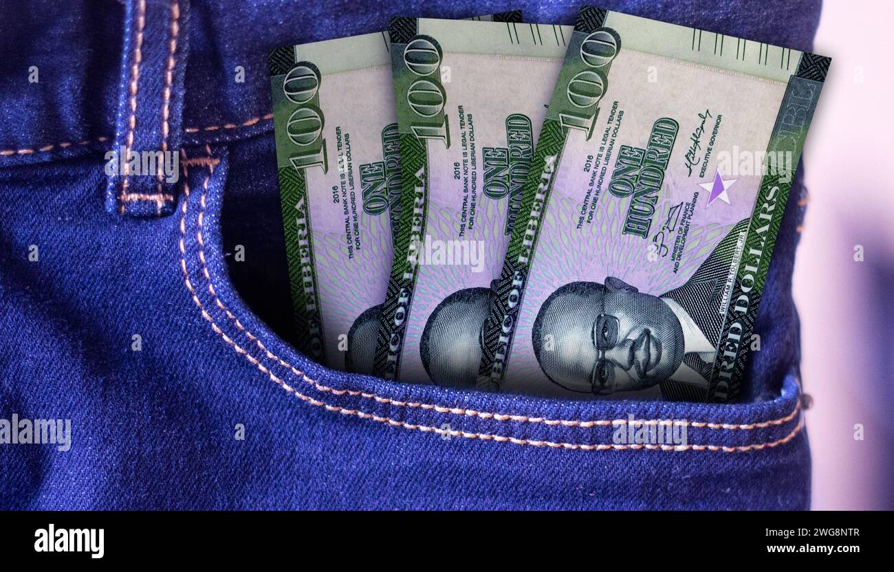 Un mucchio di banconote da 100 dollari della Liberia in una tasca di jeans un concetto di spesa Foto Stock