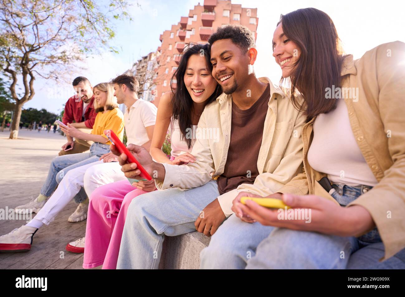 Gruppo giovane di gente gen z che si diverte usando il cellulare insieme fuori.felice comunità di studenti Foto Stock