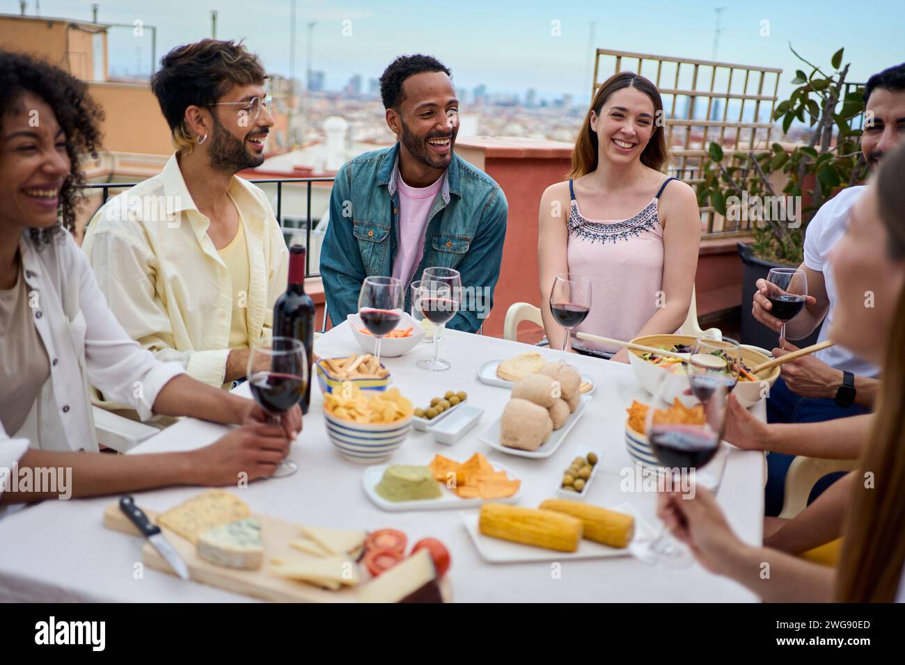 Gruppo felice di giovani amici multirazziali che si divertono a pranzare insieme all'aperto per festeggiare uno spuntino Foto Stock