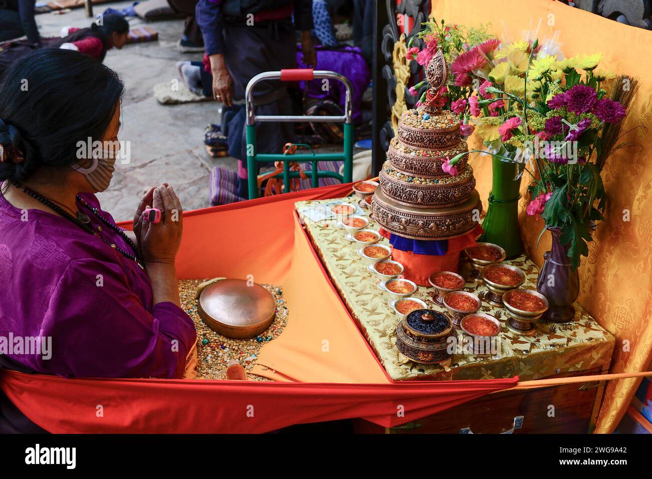 Una donna tibetana adora un piccolo altare fuori dal Tempio Jokhang a Lhasa. Foto Stock