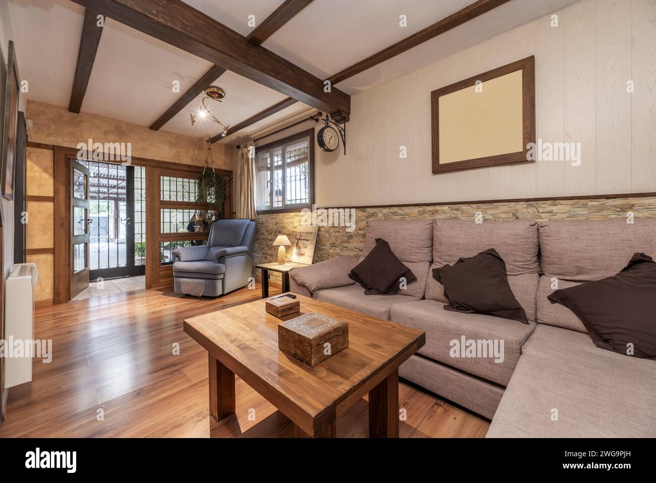 Un piccolo soggiorno al piano terra di una casa indipendente con divani rivestiti in tessuto, pavimenti in legno e travi a soffitto Foto Stock