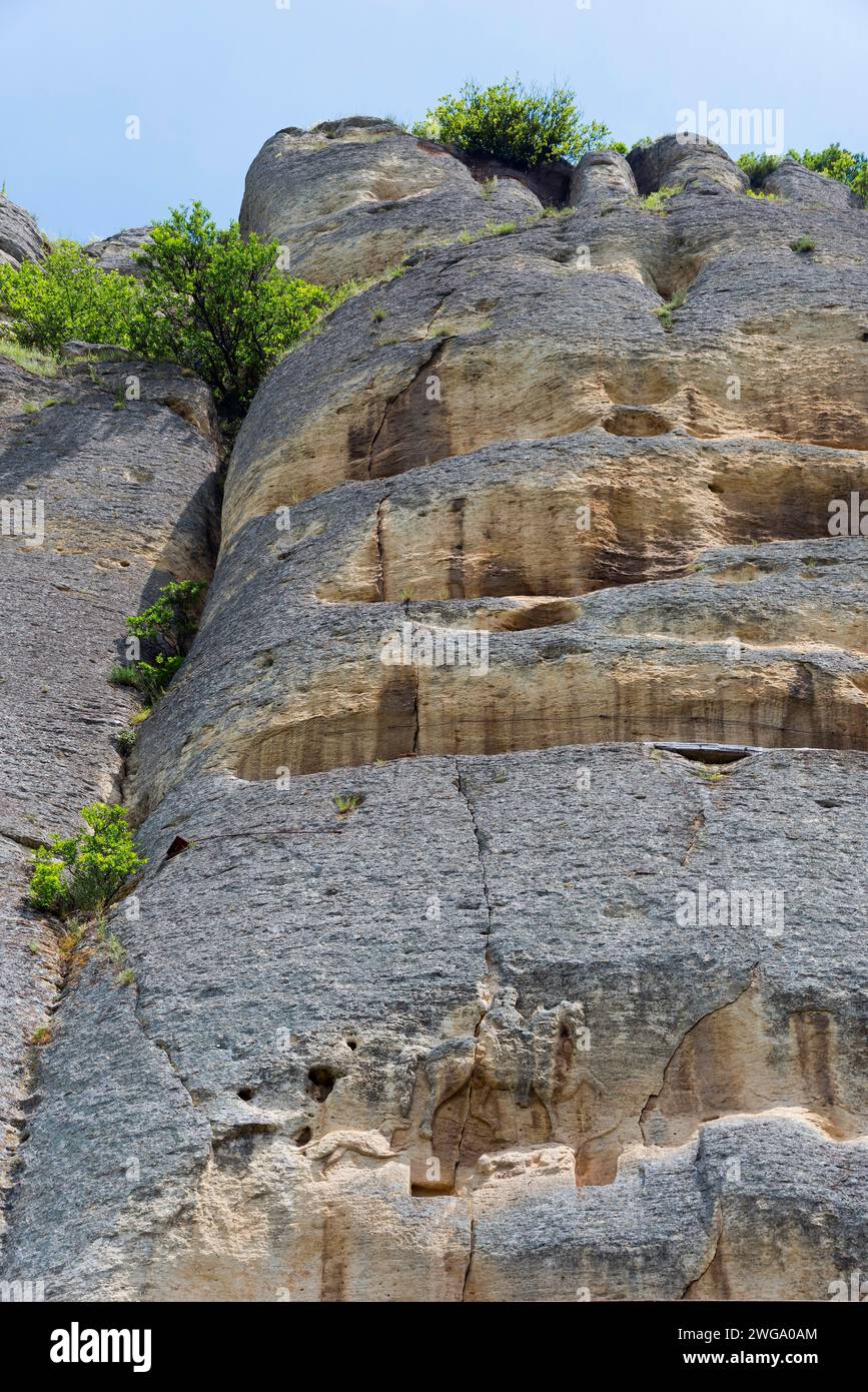 Parete rocciosa con vegetazione lussureggiante sotto un cielo blu in un'ora di sole, rilievo roccioso, Cavalieri di Madara, Madara, Shumen, Shumla, il mondo dell'UNESCO Foto Stock