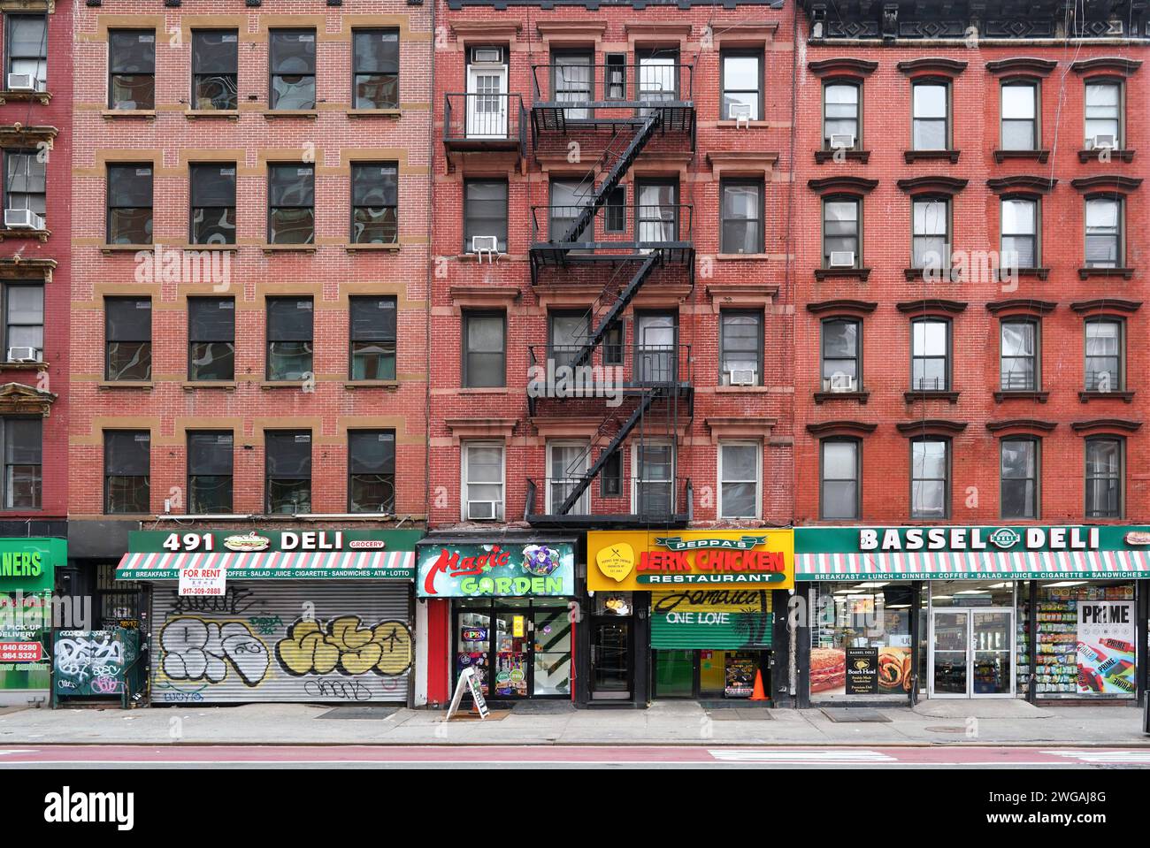 Edifici in vecchio stile di New York City con scale antincendio esterne e negozi al piano terra Foto Stock