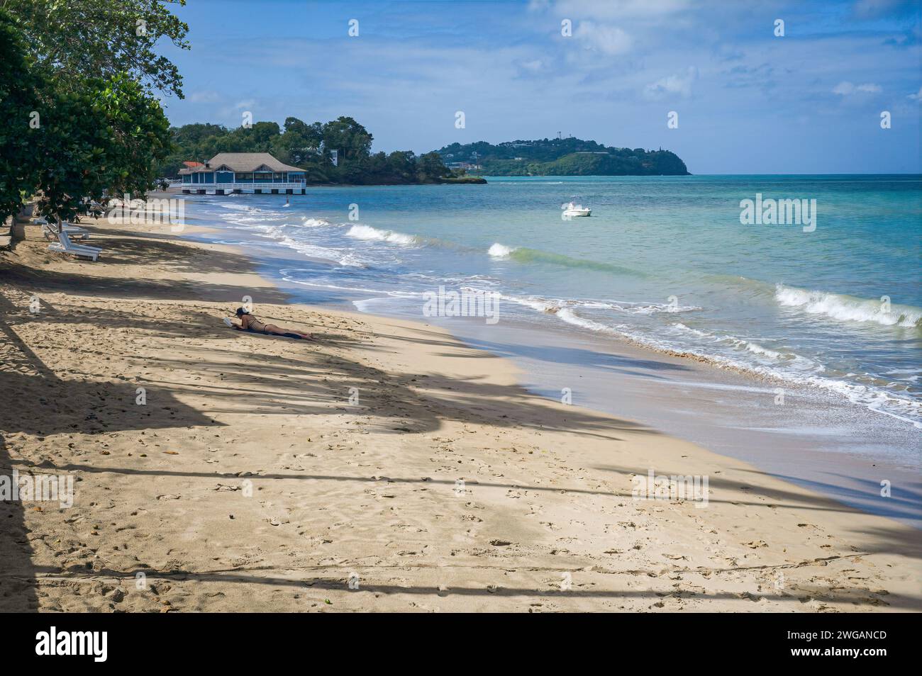 Una donna legge sulla spiaggia di Choc, situata appena fuori dalla capitale Castries, su questa isola dei Caraibi orientali. Foto Stock
