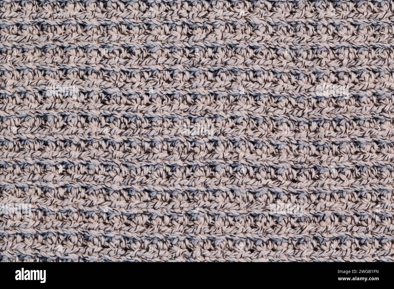 Un frammento di un caldo maglione lavorato a maglia realizzato in fili di lana in una tonalità beige. Foto Stock