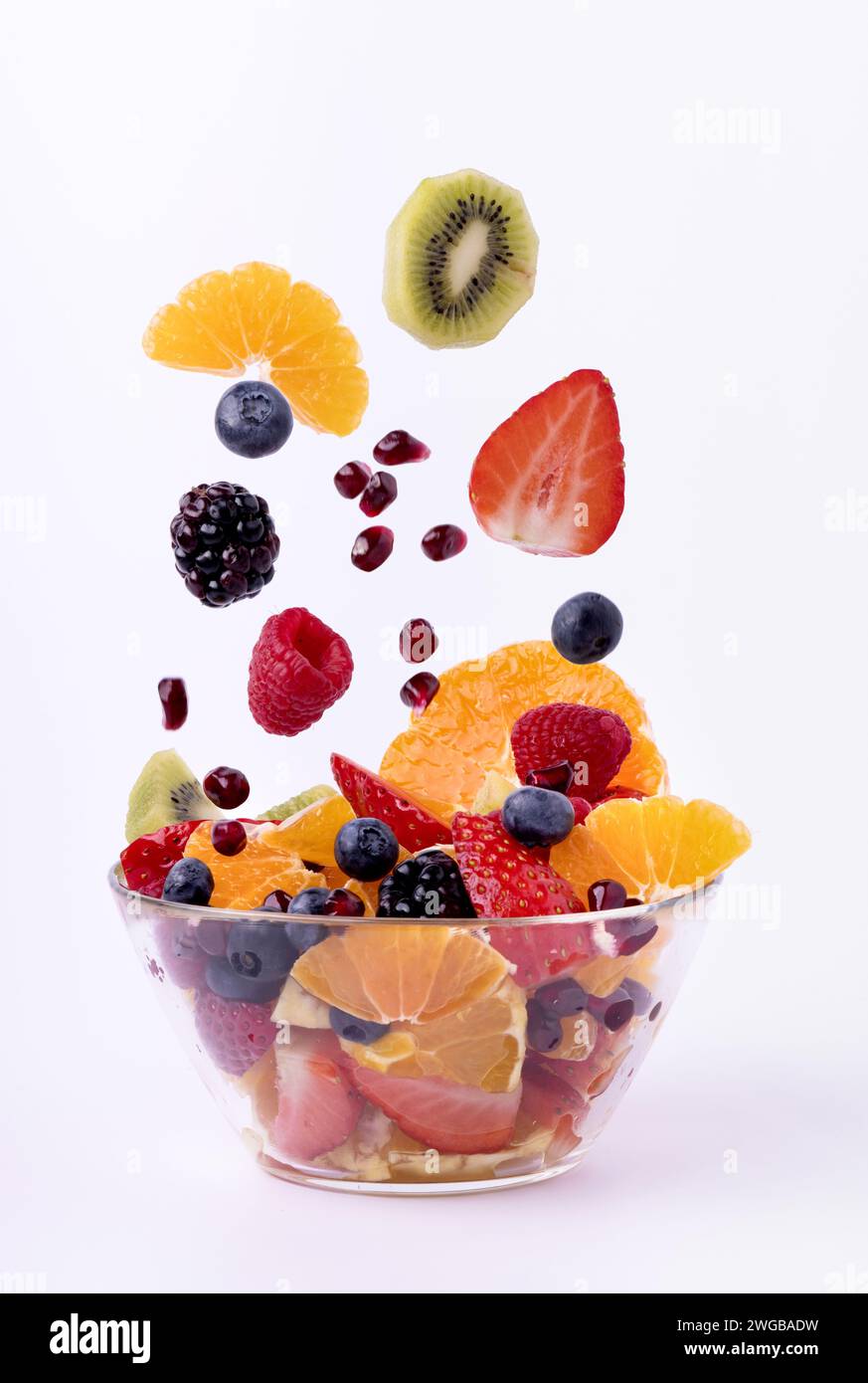 la frutta fresca mescolata a pezzi cade nel recipiente di vetro. Sfondo bianco Foto Stock