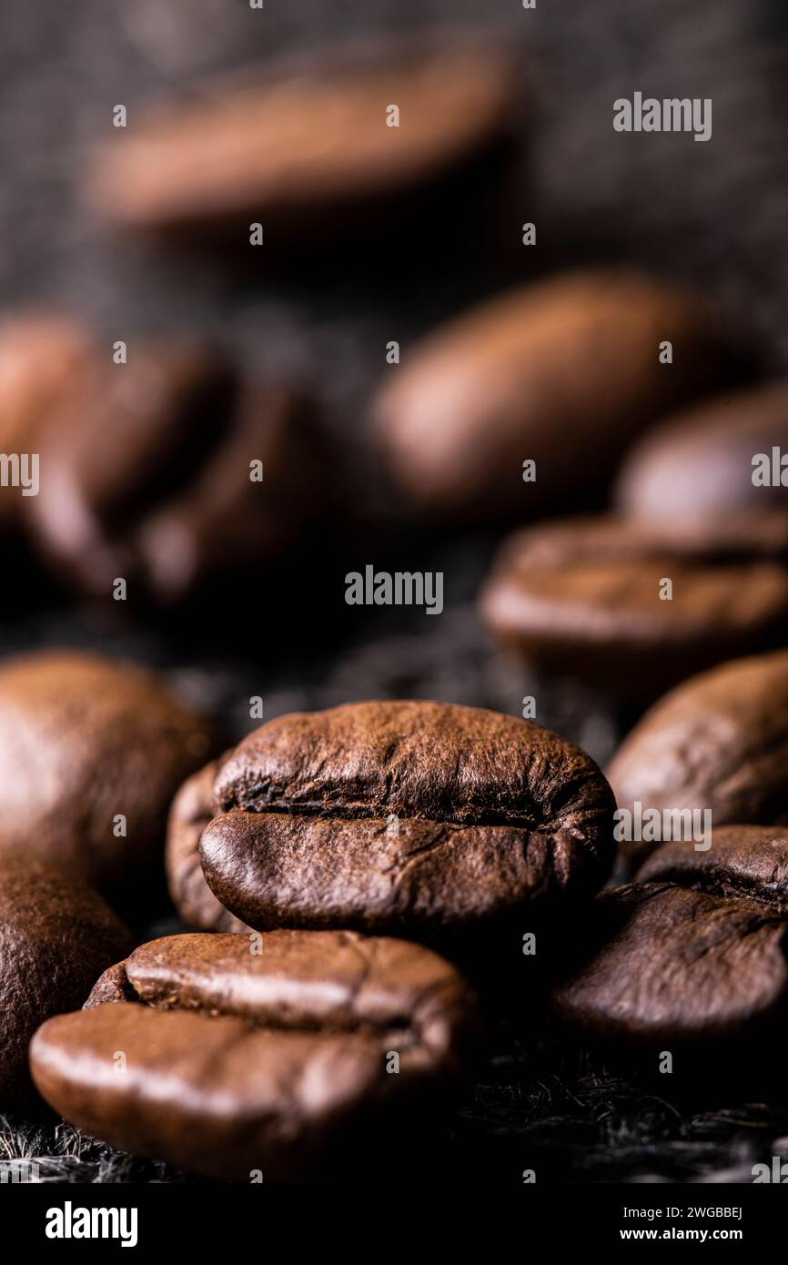Alcuni chicchi di caffè tostati in primo piano con una messa a fuoco selettiva. Foto Stock