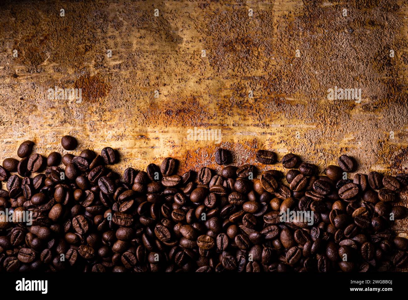 In primo piano, dall'alto, sullo sfondo rustico marrone rustico, i chicchi di caffè tostati. Spazio vuoto per il testo Foto Stock