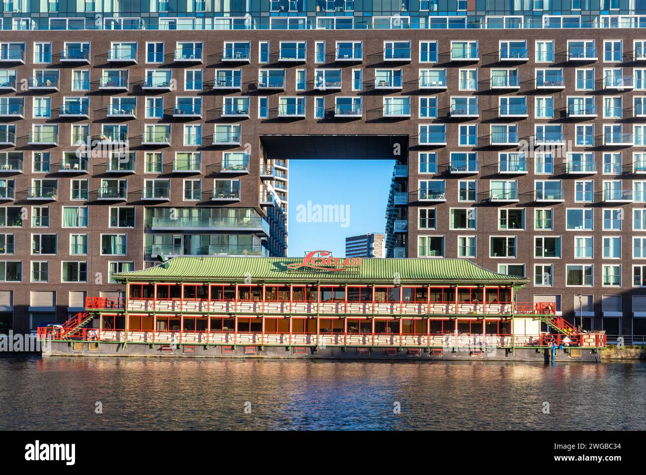 Il ristorante galleggiante Lotus sul molo interno di Millwall sull'Isola dei cani, London Docklands, Inghilterra, Regno Unito, con un edificio residenziale dietro di esso Foto Stock