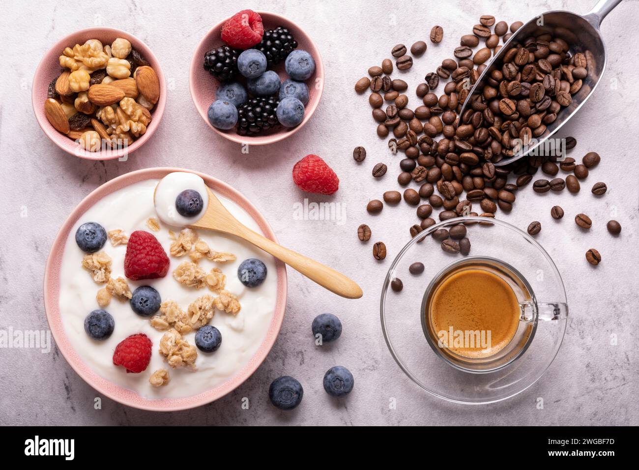 Concetto di nutrizione sana. Cibo per colazione, vista dall'alto, una ciotola con yogurt magro, farinata d'avena croccante, frutta secca, frutta fresca ed espresso. Foto Stock