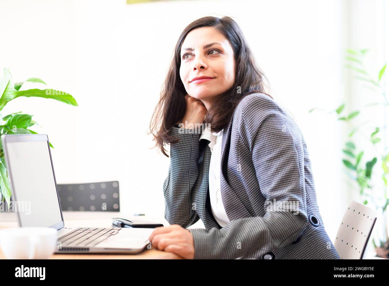 Donna d'affari seduta in un ufficio di fronte a un portatile Foto Stock