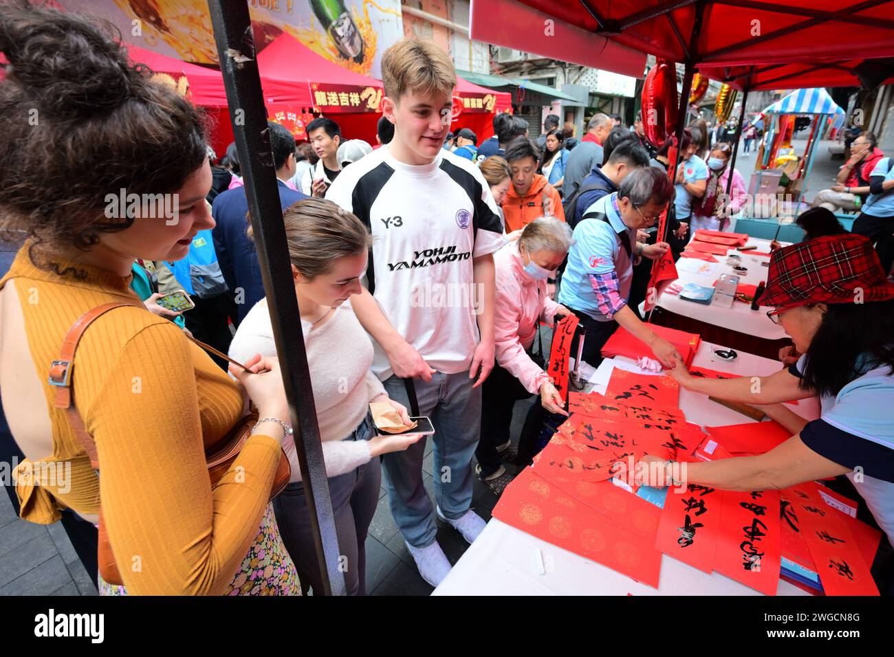 Hong Kong. 4 febbraio 2024. Gli studenti d'oltremare guardano gli artisti scrivere calligrafia cinese durante un evento che celebra il prossimo capodanno cinese presso la Temple Street a Hong Kong, nel sud della Cina, il 4 febbraio 2024. Crediti: Zhu Wei/Xinhua/Alamy Live News Foto Stock