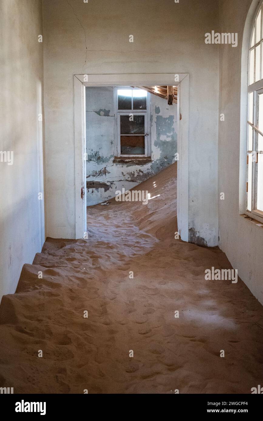 La sabbia che copre il pavimento di un corridoio abbandonato in una vecchia città deserta Foto Stock