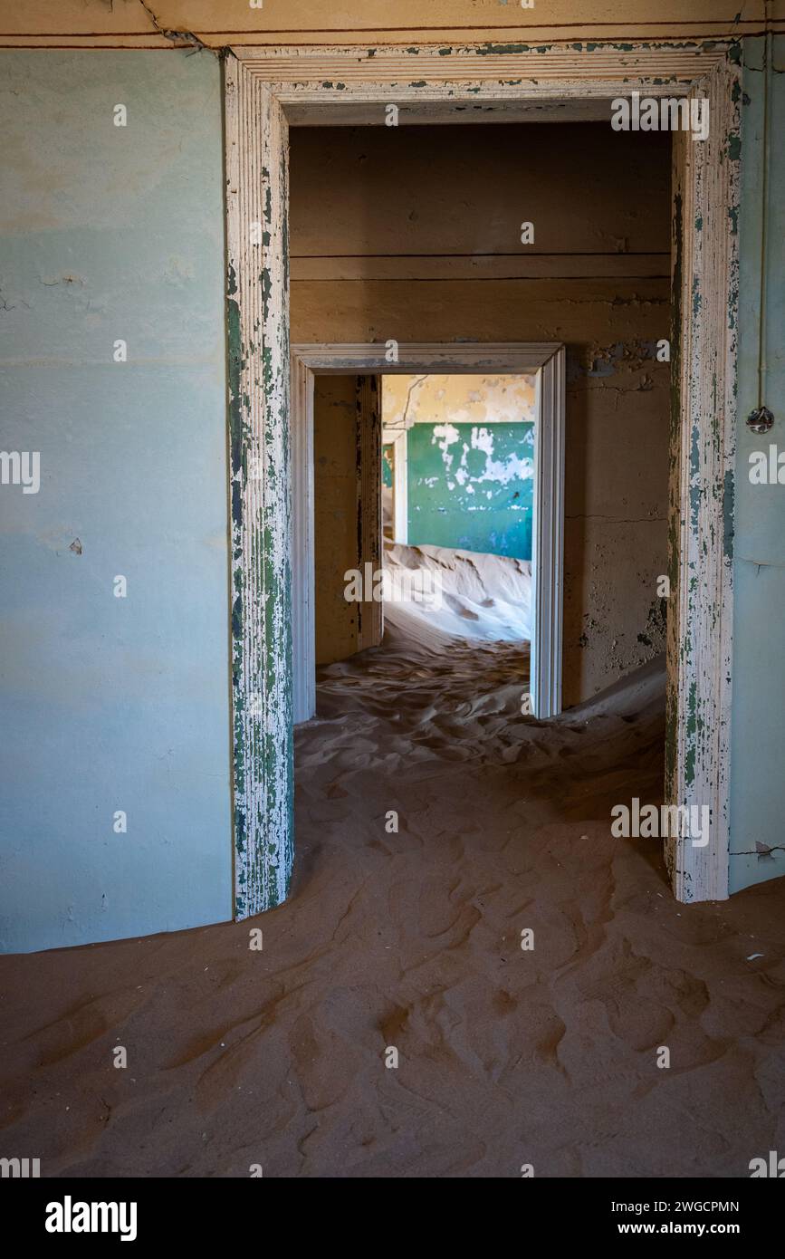 Una porta aperta rivela una camera con pavimento sabbioso, in una vecchia città deserta Foto Stock