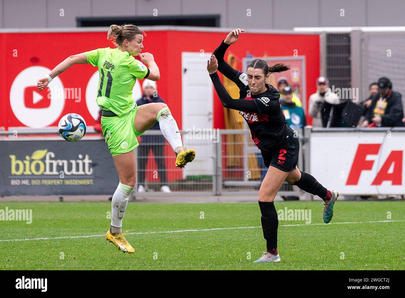 Alexandra Popp (VfL Wolfsburg, n. 11) verpasst den Ball und Selina Ostermeier (Bayer 04 Leverkusen, n. 02) reisst die Arme hoch um sich zu schuetzen. Fussball: Google Pixel Frauen-Bundesliga, Saison 2023/2024, 12. Spieltag, Bayer 04 Leverkusen - VfL Wolfsburg am 04.02.2024 im Ulrich-Haberland-Stadion a Leverkusen. Wichtiger Hinweis: Gemaess den Vorgaben der DFL Deutsche Fussball Liga bzw. Des DFB Deutscher Fussball-Bund ist es untersagt, in dem Stadion und/oder vom Spiel angefertigte Fotoaufnahmen in forma von Sequenzbildern und/oder videoaehnlichen Fotostrecken zu verwerten bzw. verwerten zu lass Foto Stock
