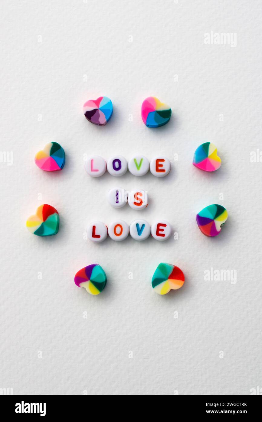 Phrase Love è l'amore fatto con perline colorate per realizzare collane e braccialetti circondati da cuori Foto Stock