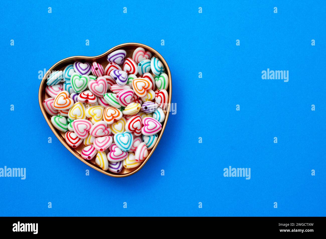Contenitore con perline dalle linee colorate per realizzare collane e bracciali a forma di cuore Foto Stock