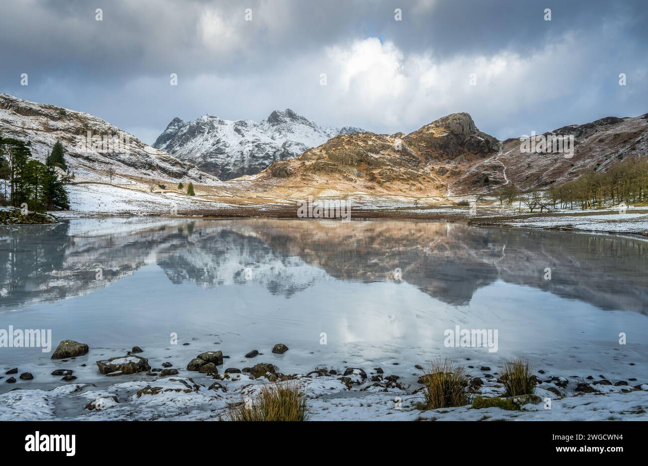 Langdale Pikes e Side Pike si riflettono in un Blea Tarn ghiacciato Foto Stock