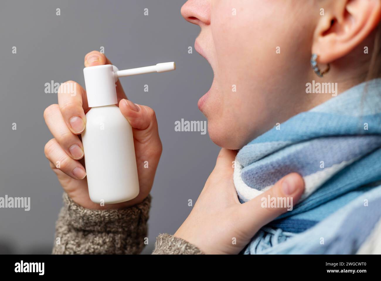 Persona che utilizza lo spray per la gola per il sollievo dal mal di gola Foto Stock