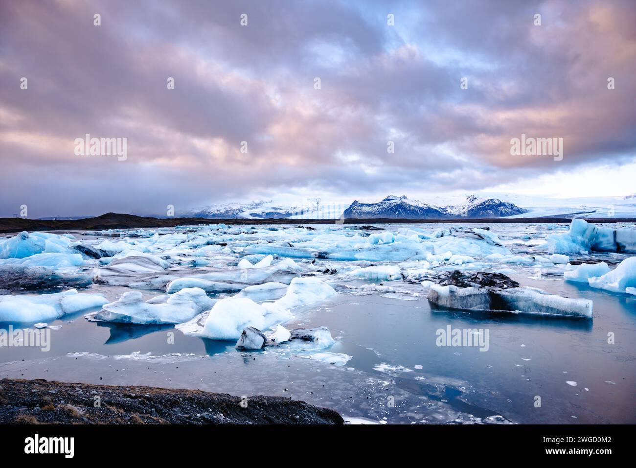 Una laguna glaciale Jokulsarlon con montagne e neve sullo sfondo Foto Stock