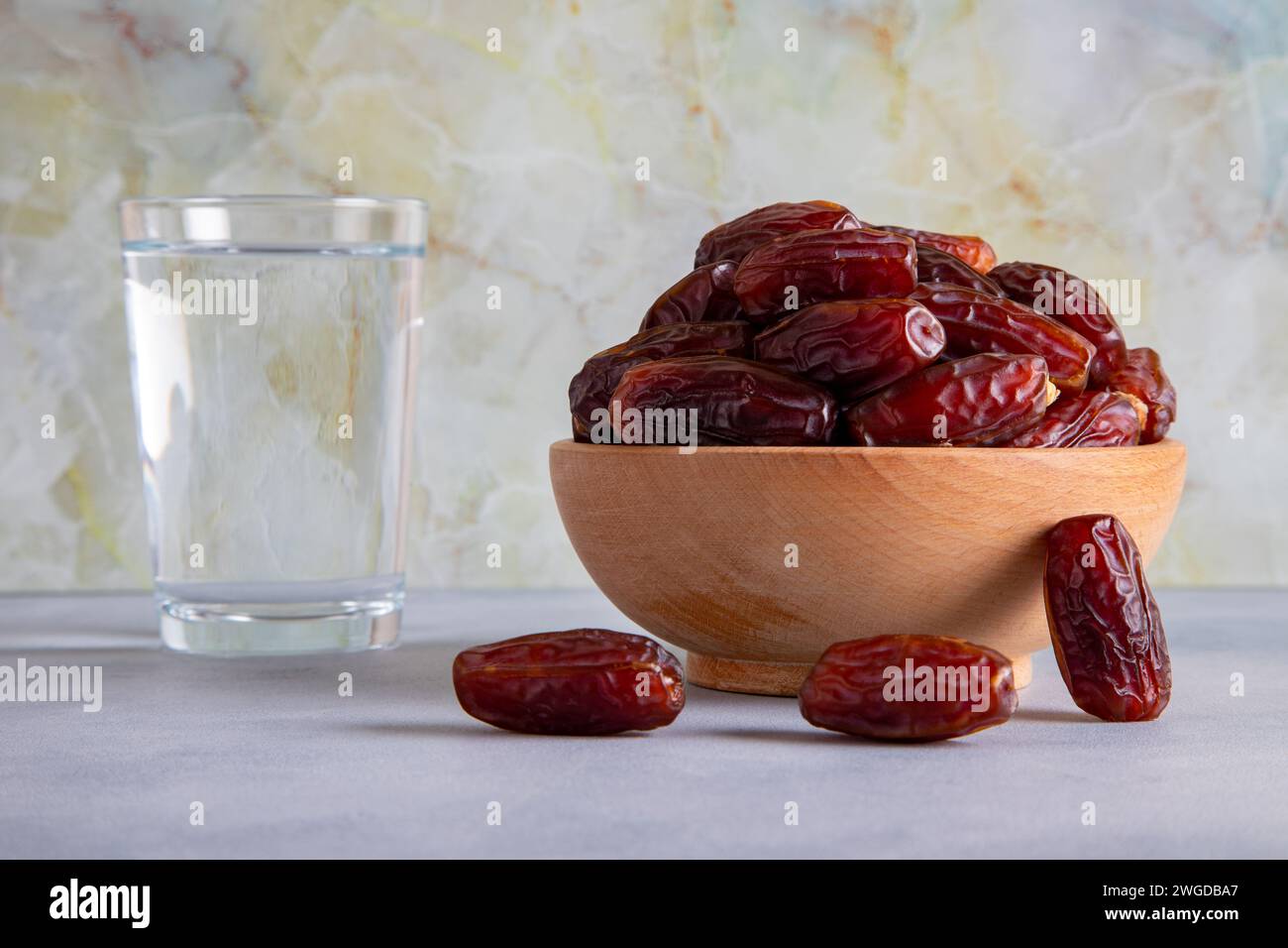 Tradizionale tabella iftar con datteri e un bicchiere d'acqua, di fronte a uno sfondo luminoso Foto Stock