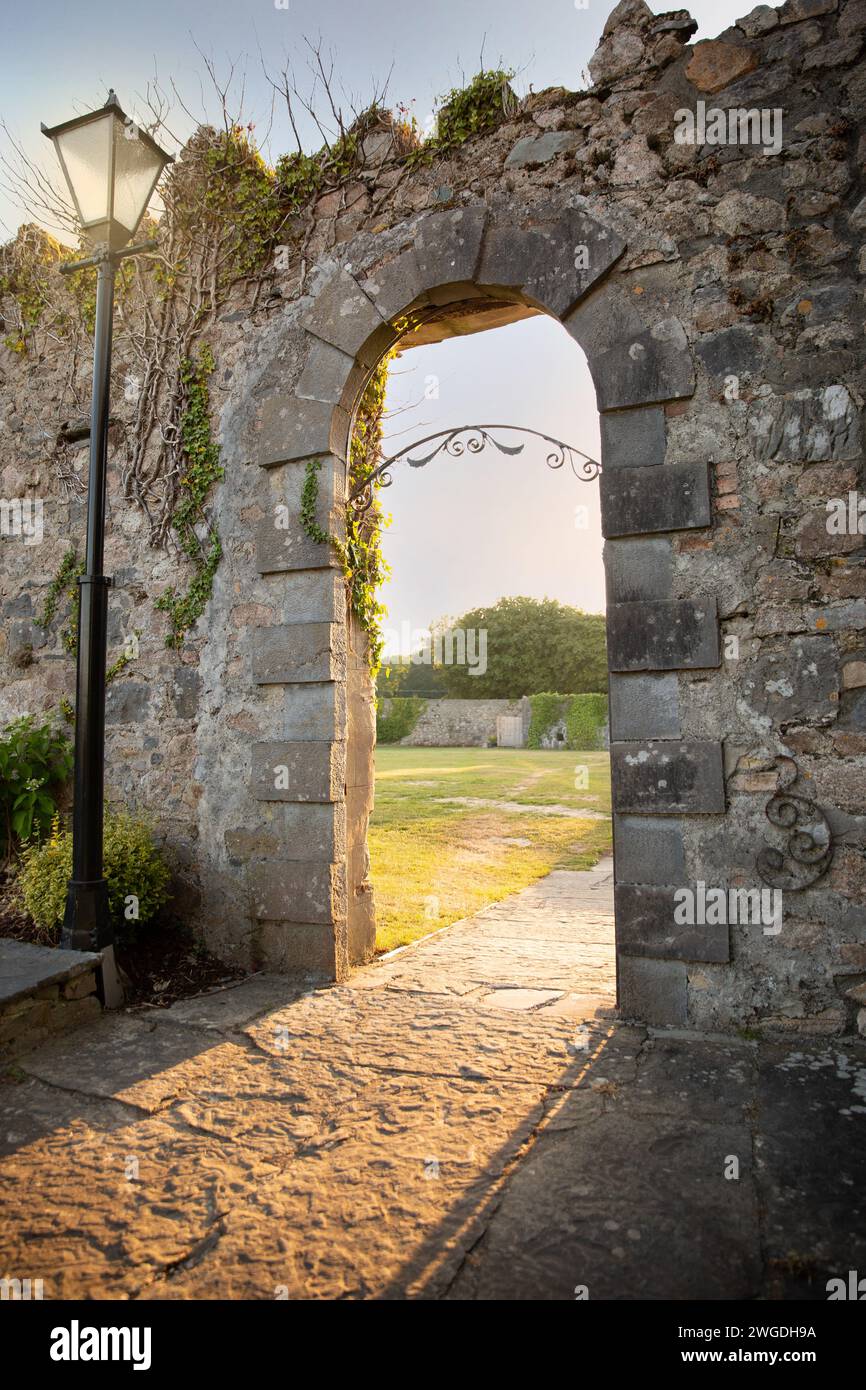 La luce del tardo giorno brilla attraverso un arco in pietra Foto Stock