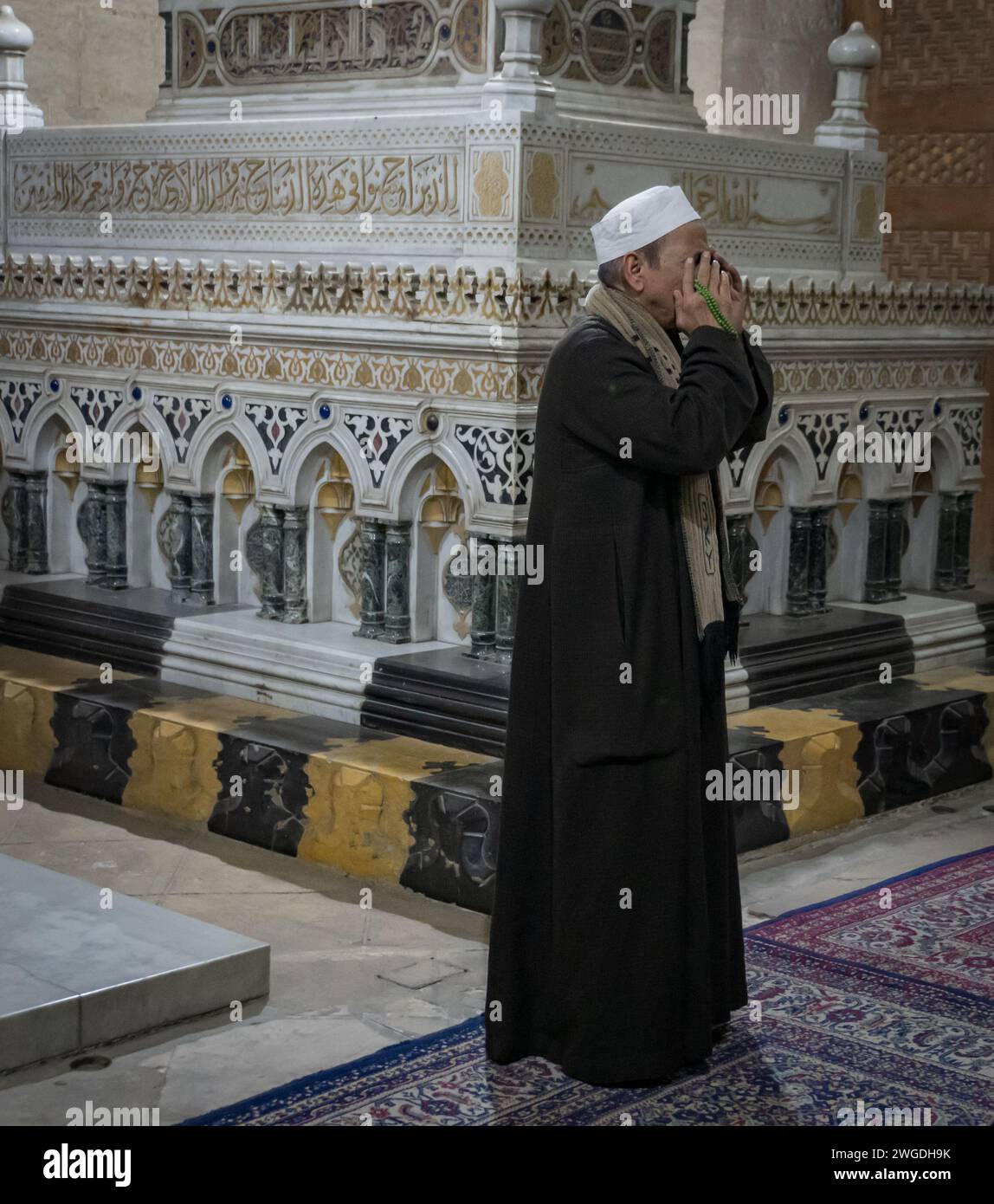 Muezzin: L'uomo musulmano che si tiene per mano davanti alla bocca mentre canta la chiamata alla preghiera in una moschea Foto Stock
