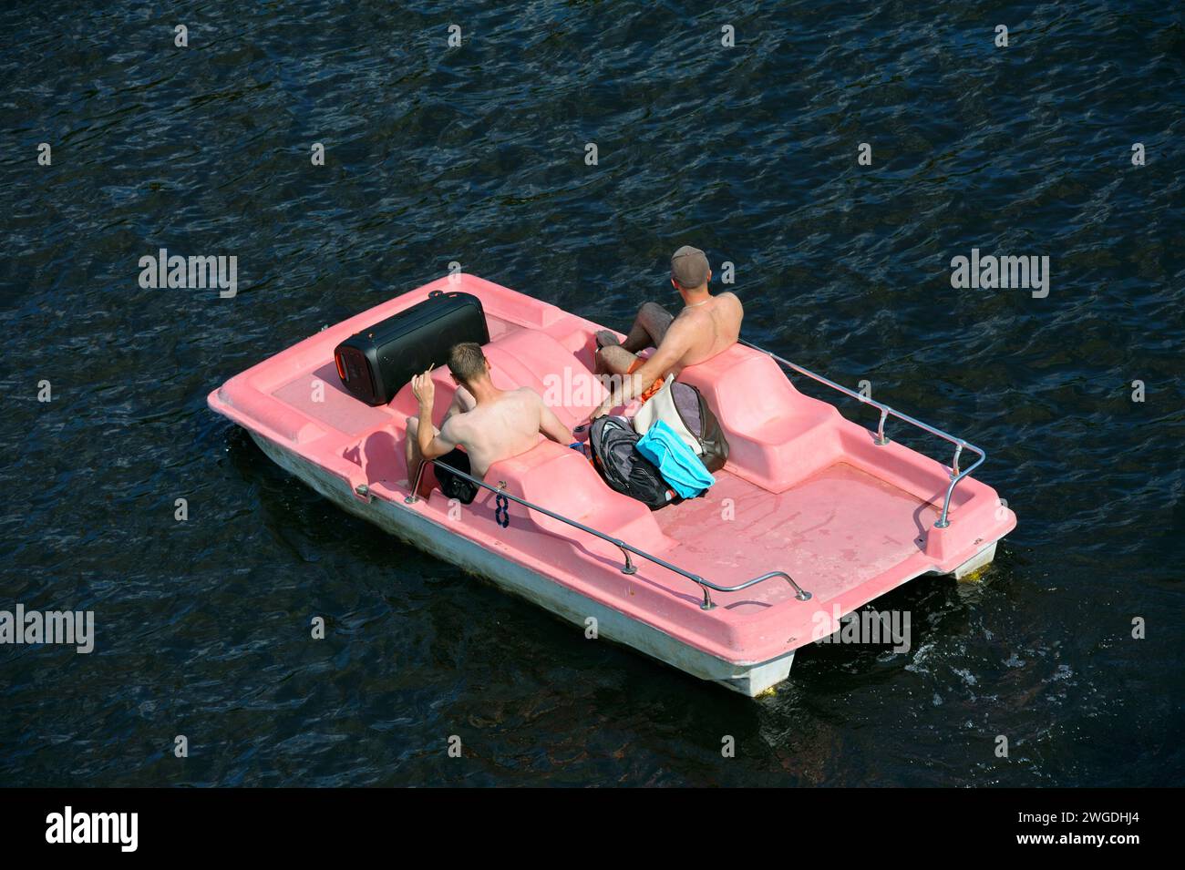 Due giovani uomini che prendono il sole pedalando sull'acqua ascoltando la musica dal boom box. 10 giugno 2021. Hydropark, Kiev Ucraina Foto Stock
