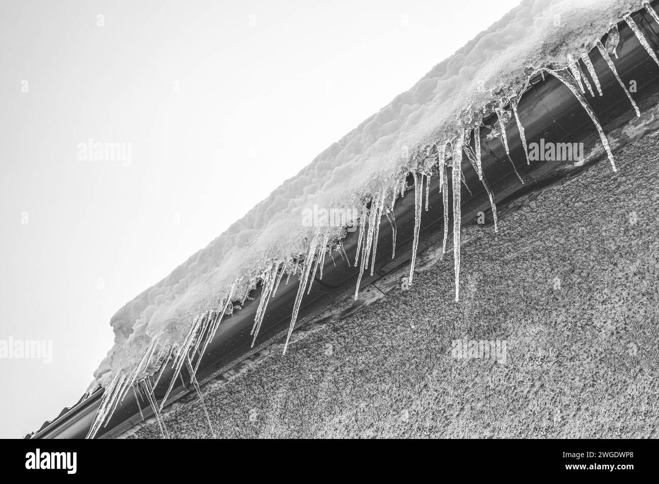 Ghiaccioli appesi al tetto sparati contro il cielo Foto Stock