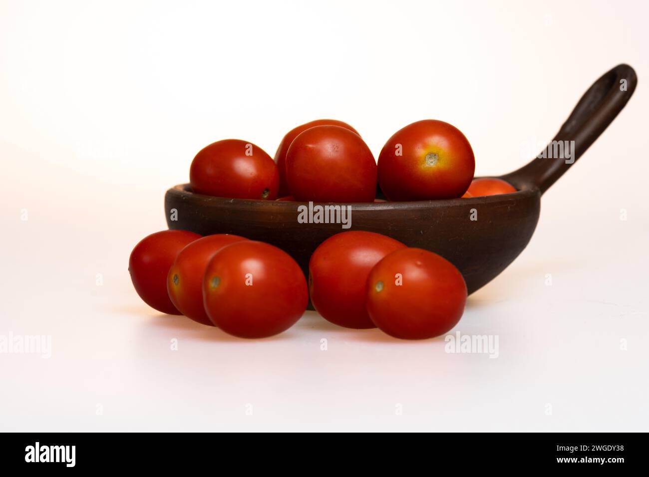 pomodori prugna in un piatto di argilla su sfondo bianco Foto Stock
