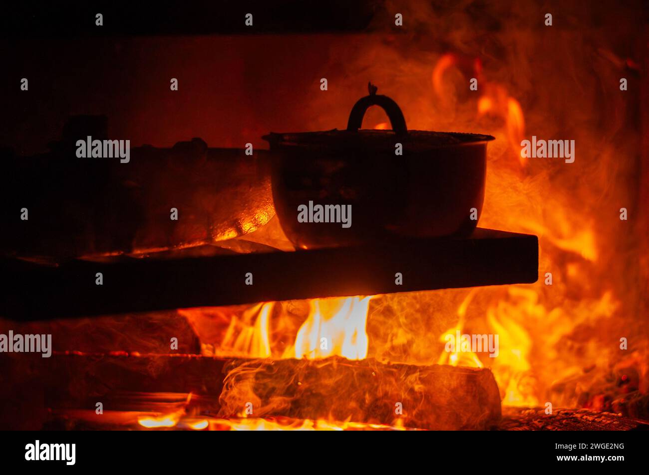 Cuocere il cibo in una pentola sopra un fuoco da campo. Una padella e una pentola in piedi su una griglia di metallo sopra un fuoco aperto. Cucinare il cibo sul fuoco. Campeggio nella foresta. Foto Stock