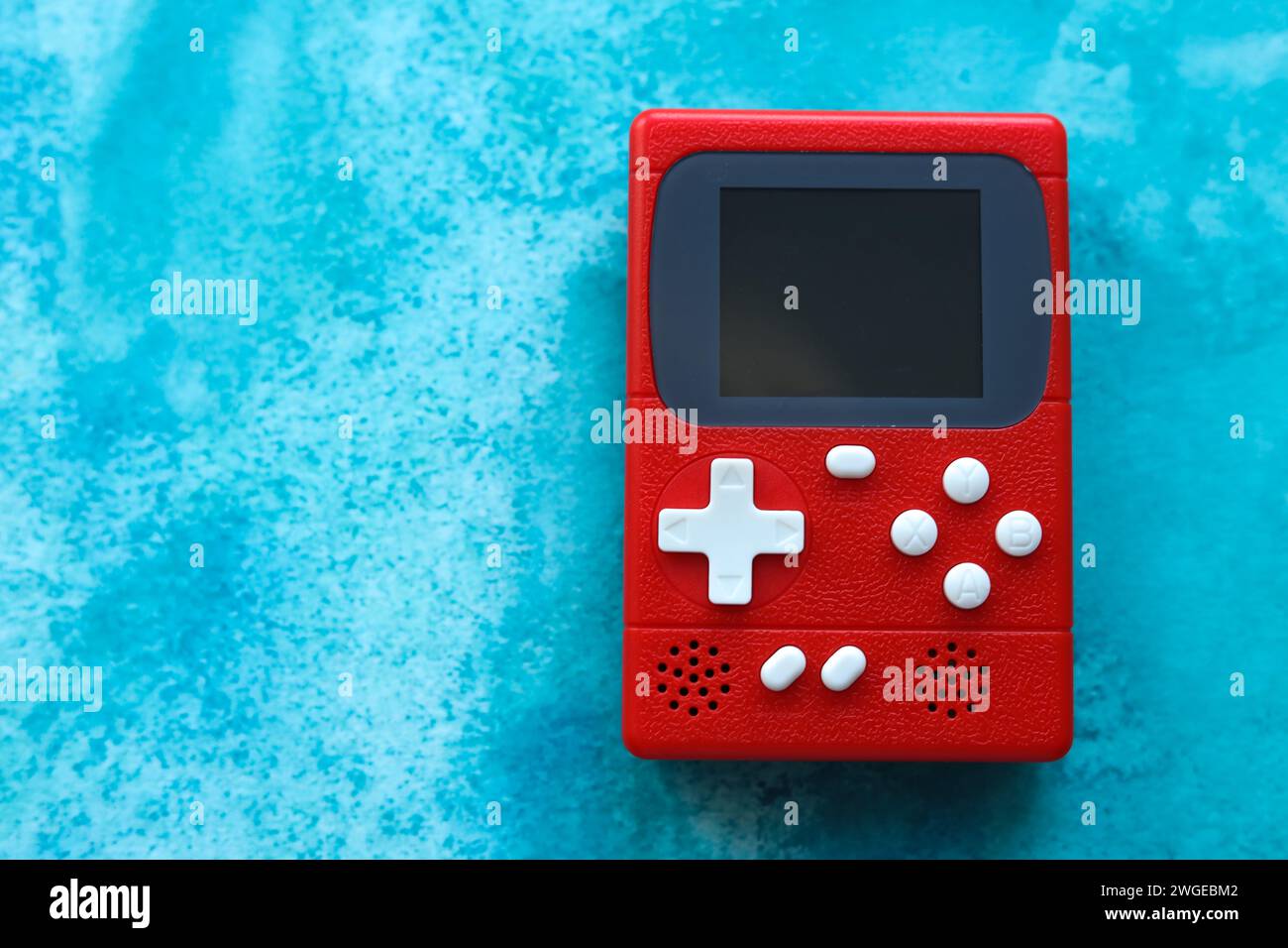 Console per videogiochi rétro su sfondo blu, vista dall'alto. Foto Stock