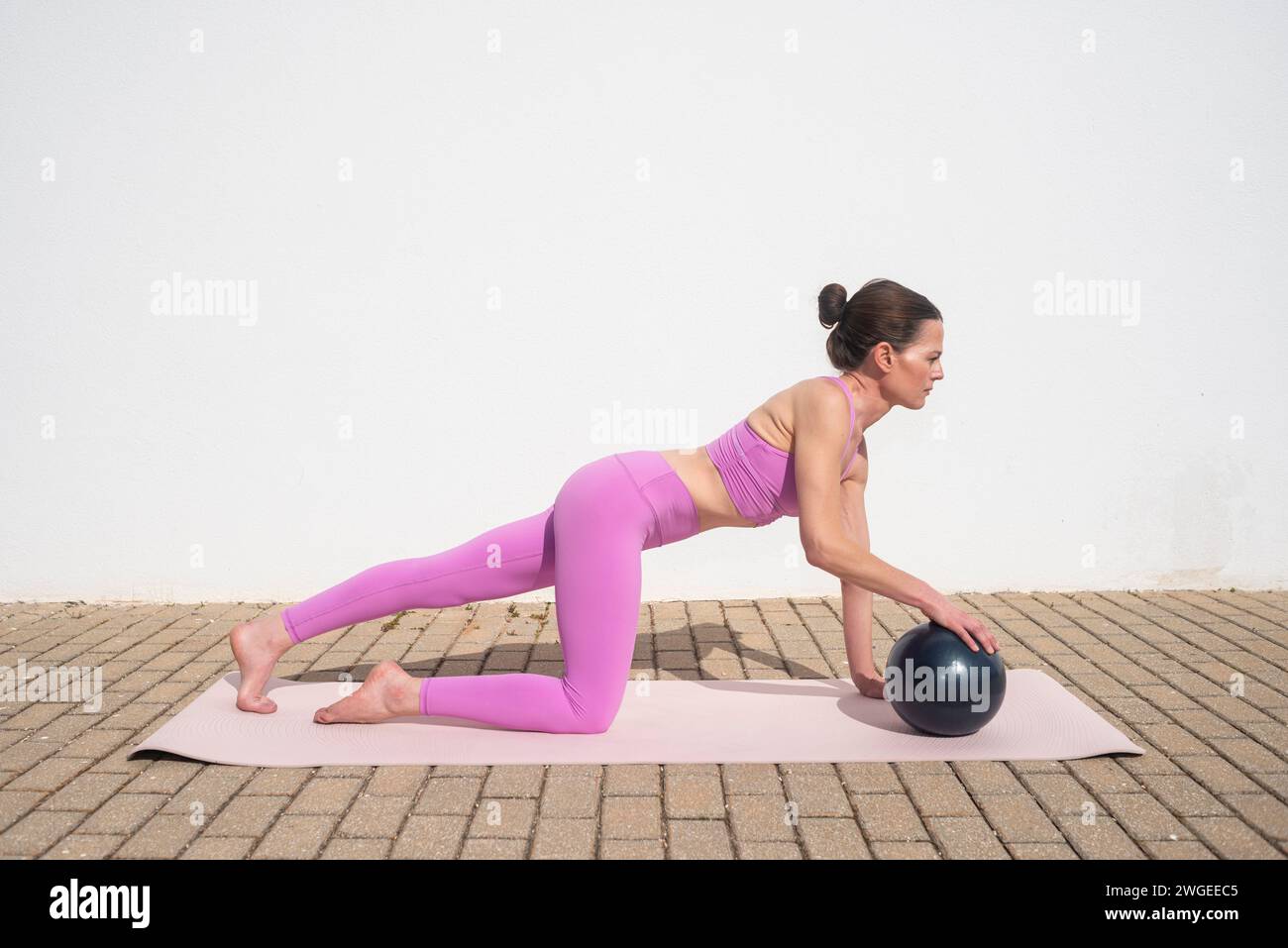 indossa una donna sportiva che fa ginnastica con palla pilates all'esterno. Preparazione Foto Stock