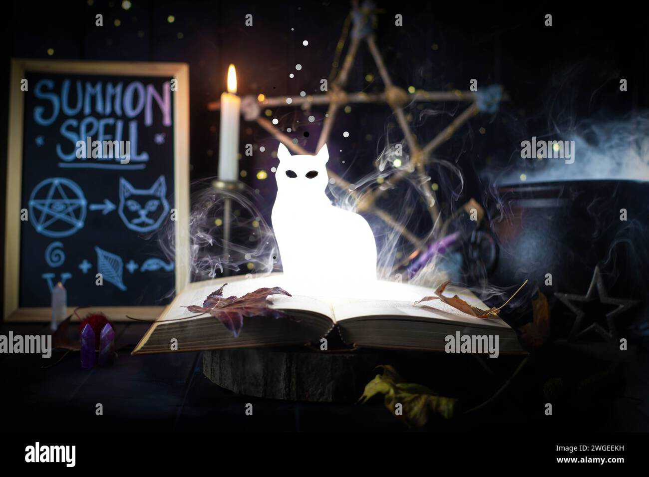 Figura gatto brillante e brillante, che si innalza da un libro in una natura morta magica con una lavagna e un calderone. Stregoneria, patronus. Foto Stock
