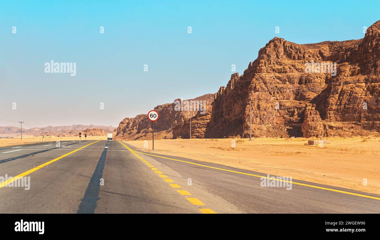 Strada panoramica nella regione di Alula in Arabia Saudita, deserto con formazioni rocciose sui lati, cielo limpido sopra Foto Stock