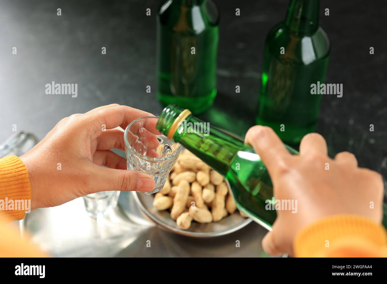 Versare acqua di soju alcol coreano a piccolo bicchiere, bere stile di vita. Messa a fuoco selettiva Foto Stock