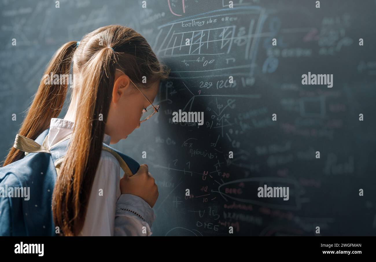 Torna a scuola. Bambino infelice al chiuso. La ragazza sta imparando in classe sulla lavagna. Foto Stock