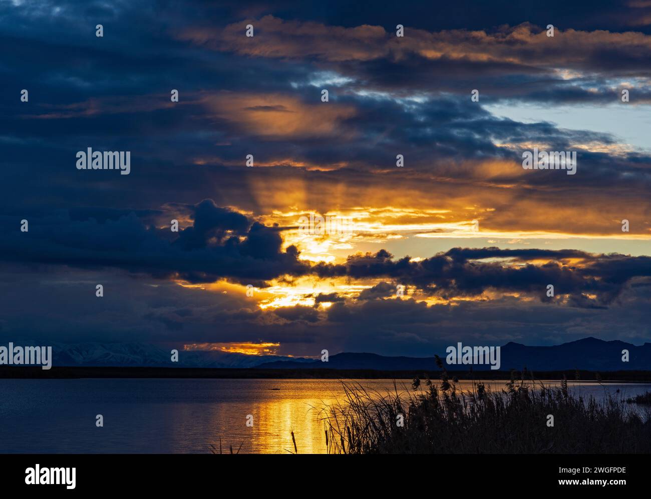 Il sole che tramonta illumina le nuvole nella Turpin Unit della Farmington Bay Waterfowl Management area, Farmington, Davis County, Utah, USA. Foto Stock