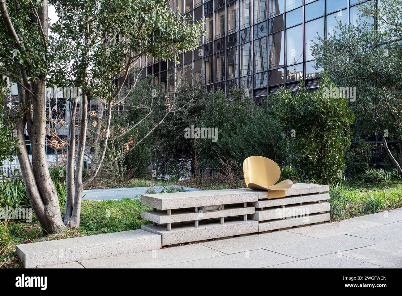 Una sedia in un parco cittadino di fronte ad un edificio moderno Foto Stock