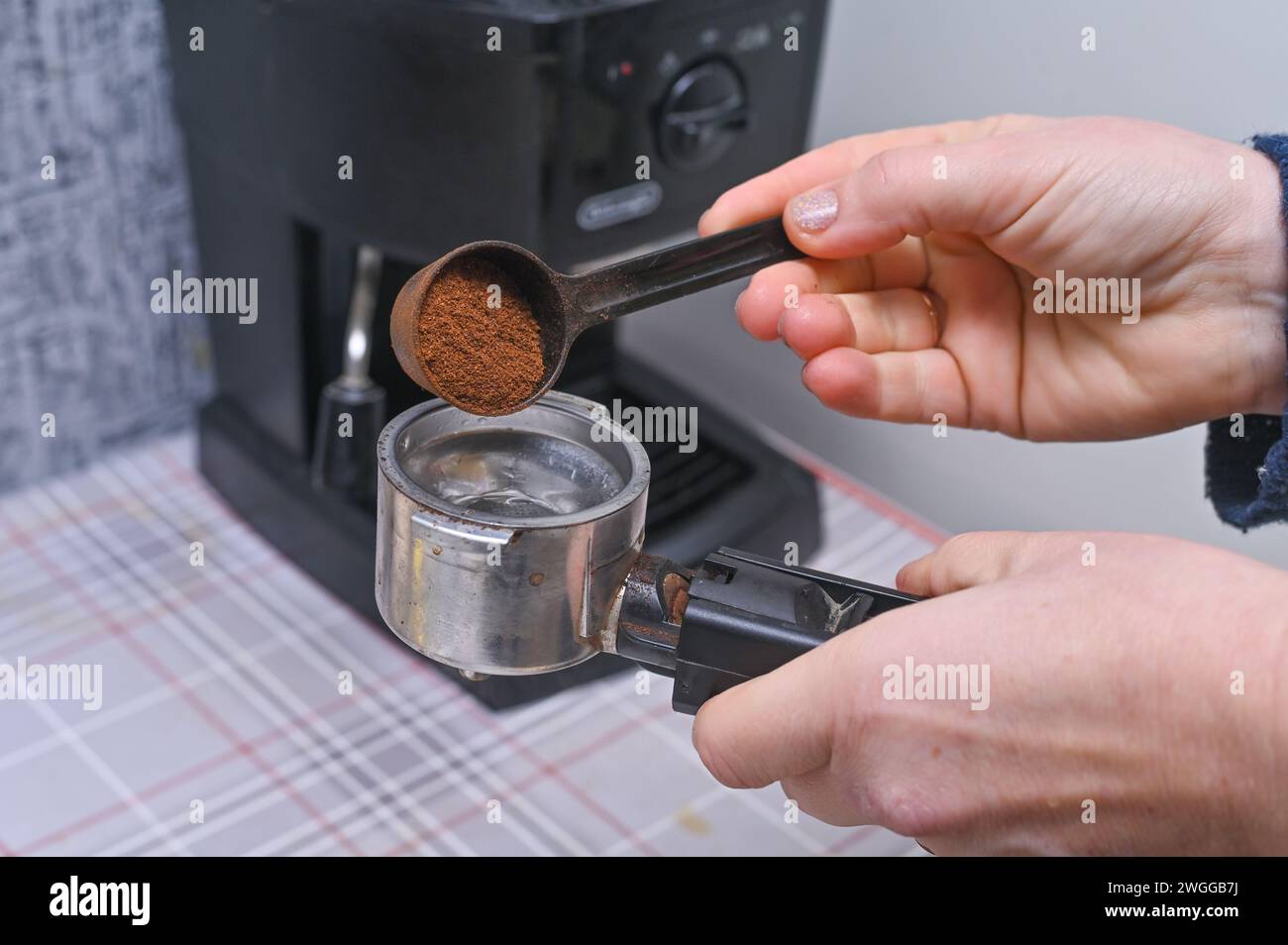 le mani delle donne versano caffè profumato nel portafiltro della macchina per caffè Foto Stock