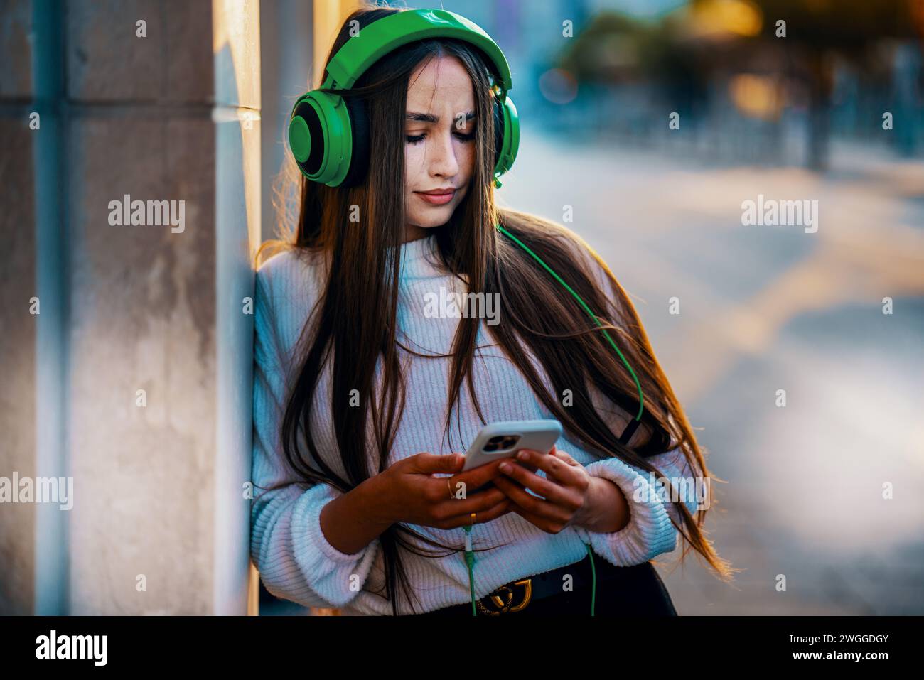 Donna felice che ascolta musica su smartphone in città Foto Stock