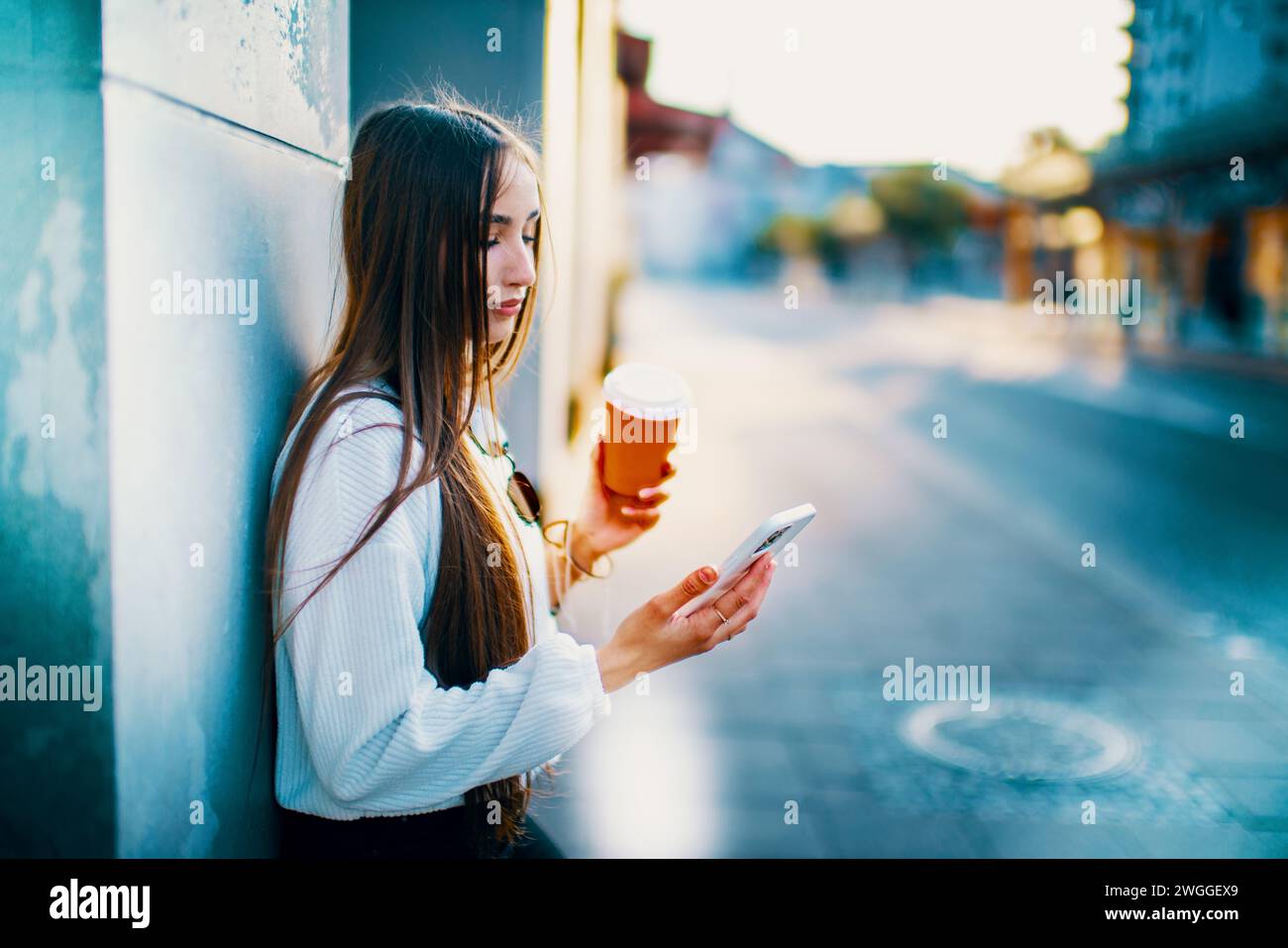 Giovane donna in abbigliamento casual che si gusta una tazza di caffè in città. Foto Stock