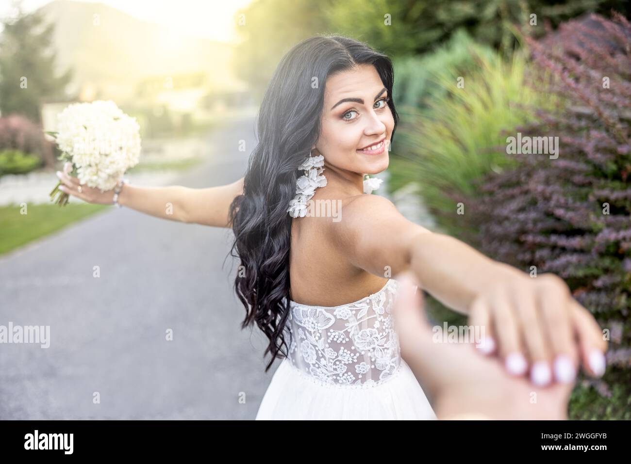 La sposa felice tira per mano suo marito verso la loro nuova vita. Foto Stock