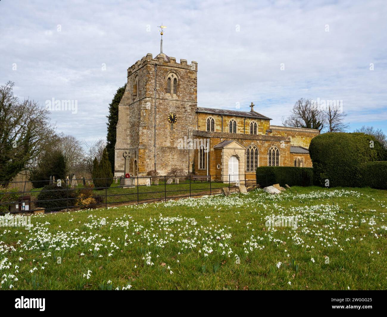 La chiesa di tutti i Santi vista dal terreno di Lamport Hall, Northamptonshire, Regno Unito; con un tappeto di nevicate in primo piano Foto Stock