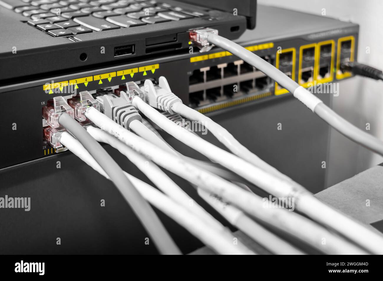 Switch Smart PoE Gigabit di rete con cavi di rete connessi al computer portatile, configurato sulla scrivania con un computer portatile Foto Stock