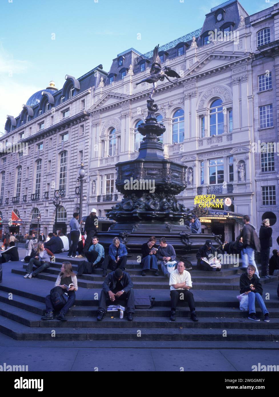 Regno Unito, Londra, Piccadilly Circus al crepuscolo, gli amanti dello shopping stanchi si riposano accanto alla statua (Shaftesbury Memorial Fountain). Foto Stock
