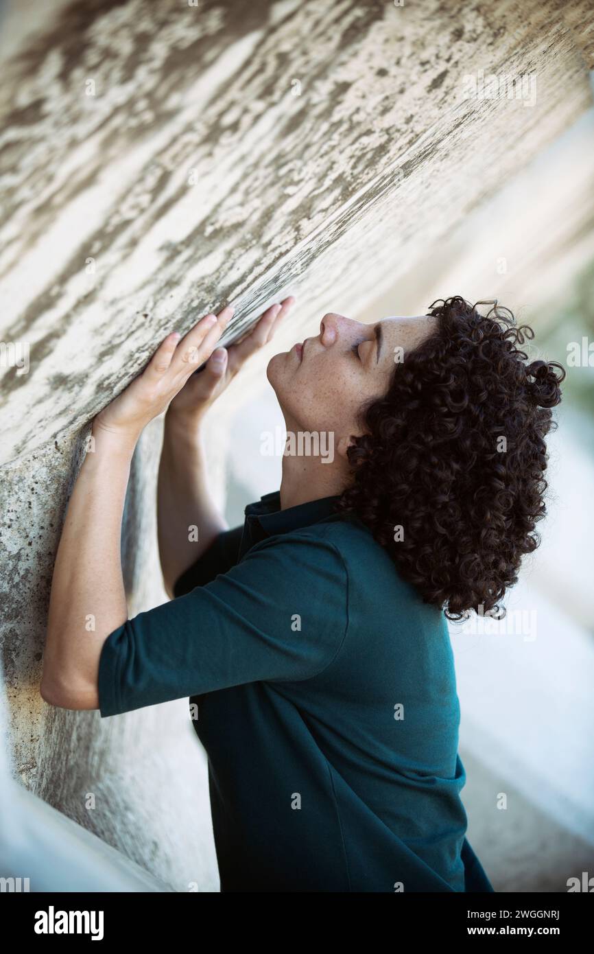 Vista laterale della donna che spinge il muro verso l'alto Foto Stock