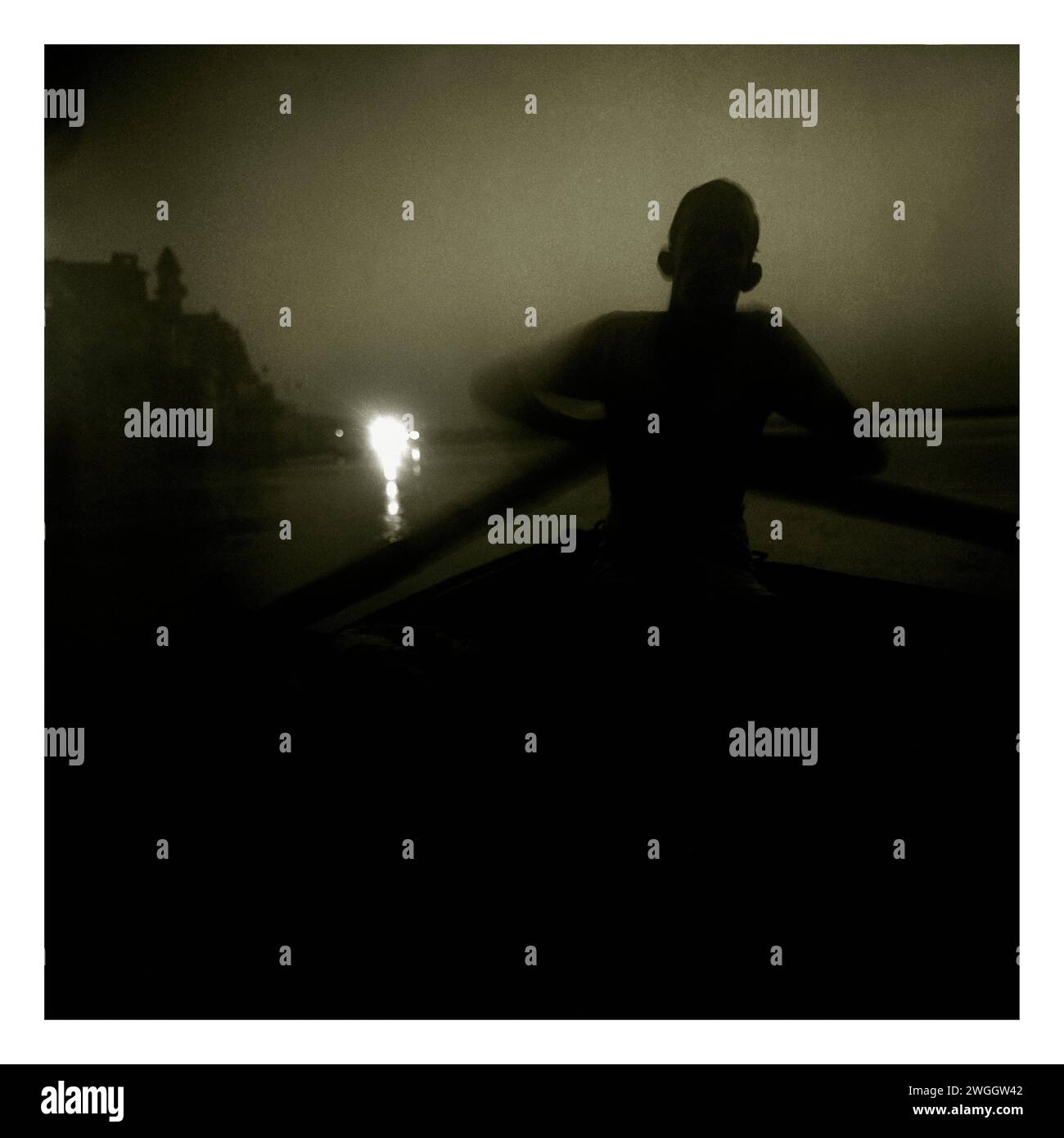 Un barcaiolo affonda la sua barca oltre il gats che costeggia il sacro fiume Gange a Varanasi. Foto Stock